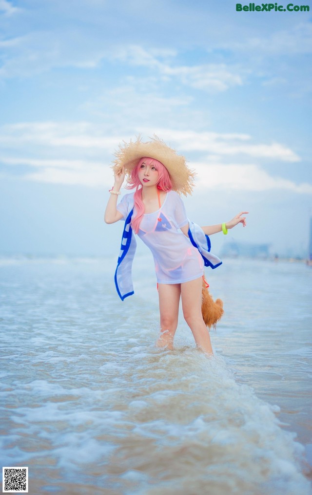 A woman in a straw hat is standing in the water.