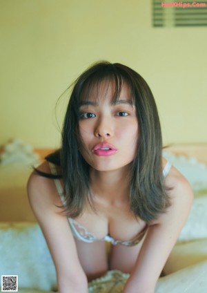 A woman sitting on a bed smiling at the camera.