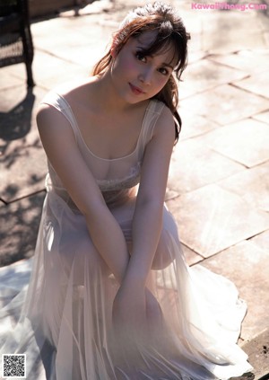A woman in a white dress sitting on a bench.