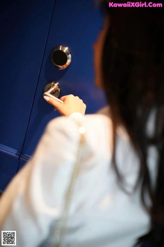 A woman is opening a blue door with a key.