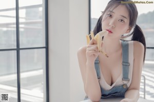 A woman sitting on a window sill eating a piece of cake.