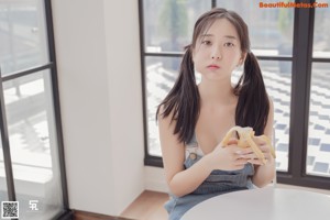 A woman sitting on a window sill eating a piece of cake.