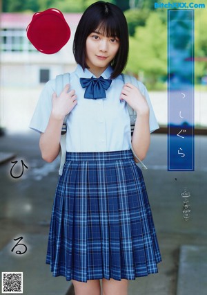 A young woman in a school uniform holding a stick.