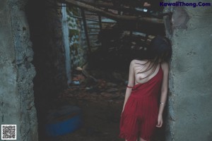 A naked woman standing in front of a stone wall.