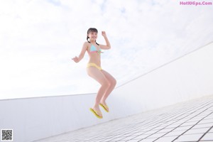 A woman in a bikini sitting on a tiled floor.