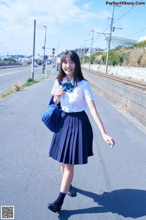 A young woman leaning against a fence with her hand on her chin.