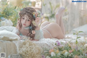 A woman sitting on a bed surrounded by flowers.