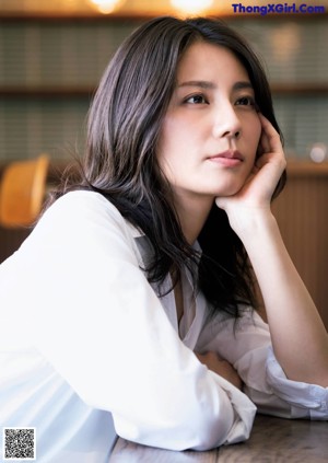 A woman in a white dress holding a cup of coffee.