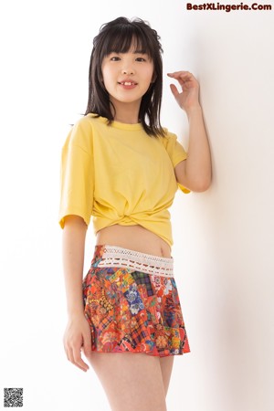 A woman in a yellow shirt and a colorful skirt.