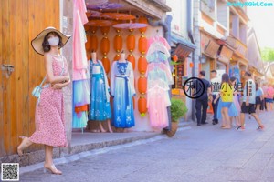 A woman in a pink dress and hat taking a selfie.