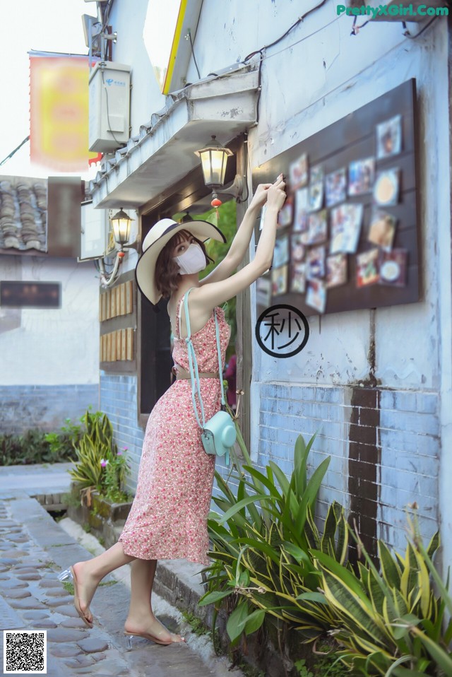 A woman in a pink dress and hat is taking a picture of herself.