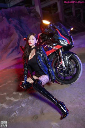 A woman in a black bodysuit sitting on a motorcycle.