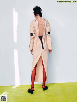 A woman in a brown coat and skirt standing on a yellow floor.