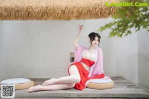 A woman in a pink kimono sitting on a wooden bench.