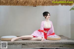 A woman in a pink kimono sitting on a wooden bench.