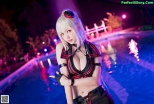 A woman in a black and red outfit posing by a pool.