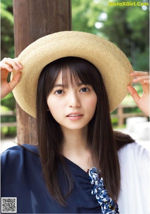 A woman wearing a straw hat is posing for a picture.