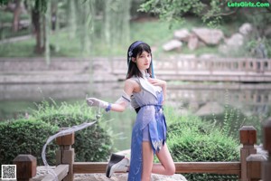 A woman in a blue and white outfit sitting on a rock.