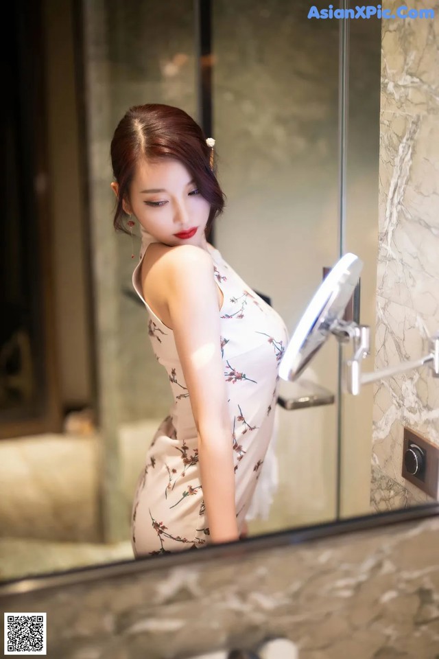 A woman standing in front of a mirror in a bathroom.