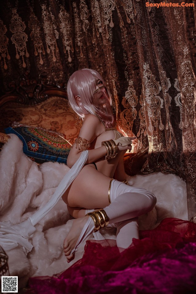 A woman sitting on top of a bed next to a curtain.