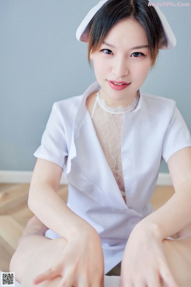 A woman in a white nurse outfit sitting on the floor.