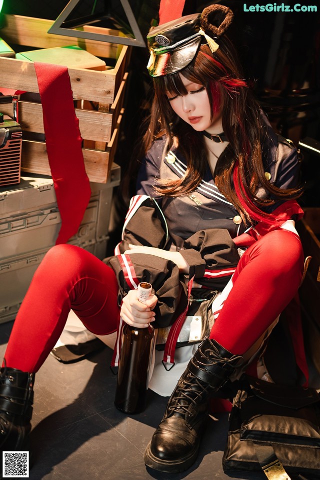 A woman sitting on the ground holding a bottle of beer.