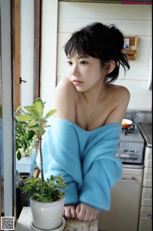 A woman sitting on a couch wearing a blue sweater.