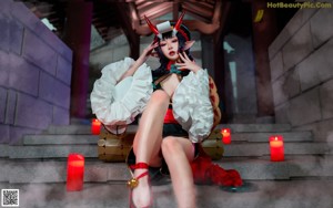 A woman dressed as a demon sitting on the ground.