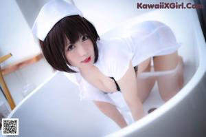 A woman in a white dress sitting in a bathtub.