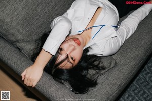 A woman sitting on a couch in front of a black and white photo.