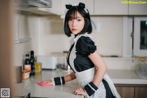 A woman in a maid outfit sitting at a table.