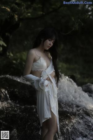 A woman in a white lingerie standing on a beach.