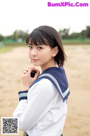 A woman in a sailor outfit holding a cell phone.