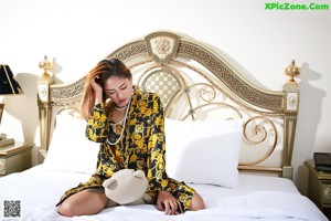 A woman sitting on top of a bed next to a teddy bear.