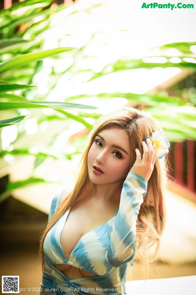 A woman in a blue and white dress holding a flower.