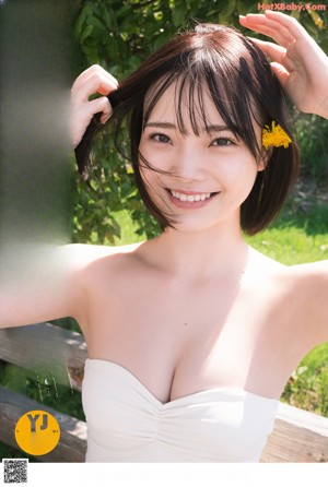 A young woman holding a dandelion in a field of flowers.