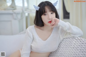 A woman in a white sweater and a white thong.