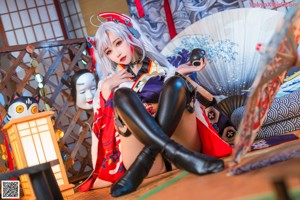 A woman in a kimono sitting on a bed.