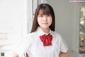 A young woman in a school uniform sitting on the floor.