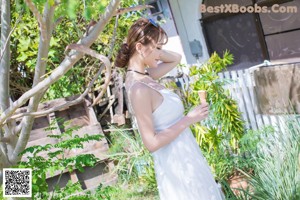 A woman leaning against a fence near the ocean.