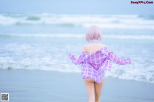 A woman in a purple and white outfit sitting on the beach.