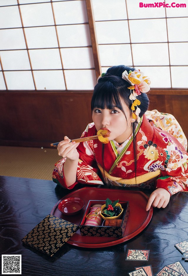 A woman in a kimono sitting at a table eating food.