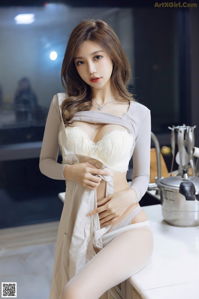 A woman in a white lingerie sitting on a kitchen counter.