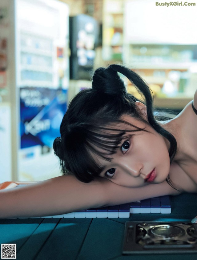 A woman laying on top of a table next to a keyboard.